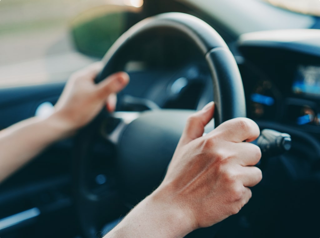 two hands on steering wheel inside of car