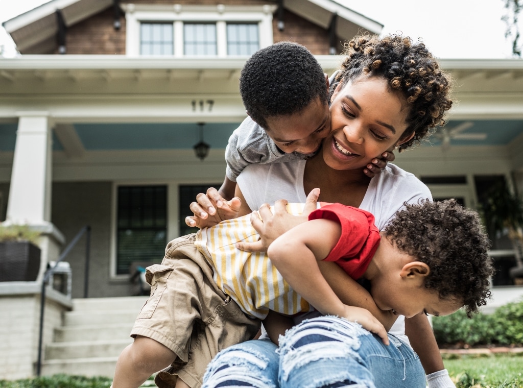 Woman with two children in front of two story house